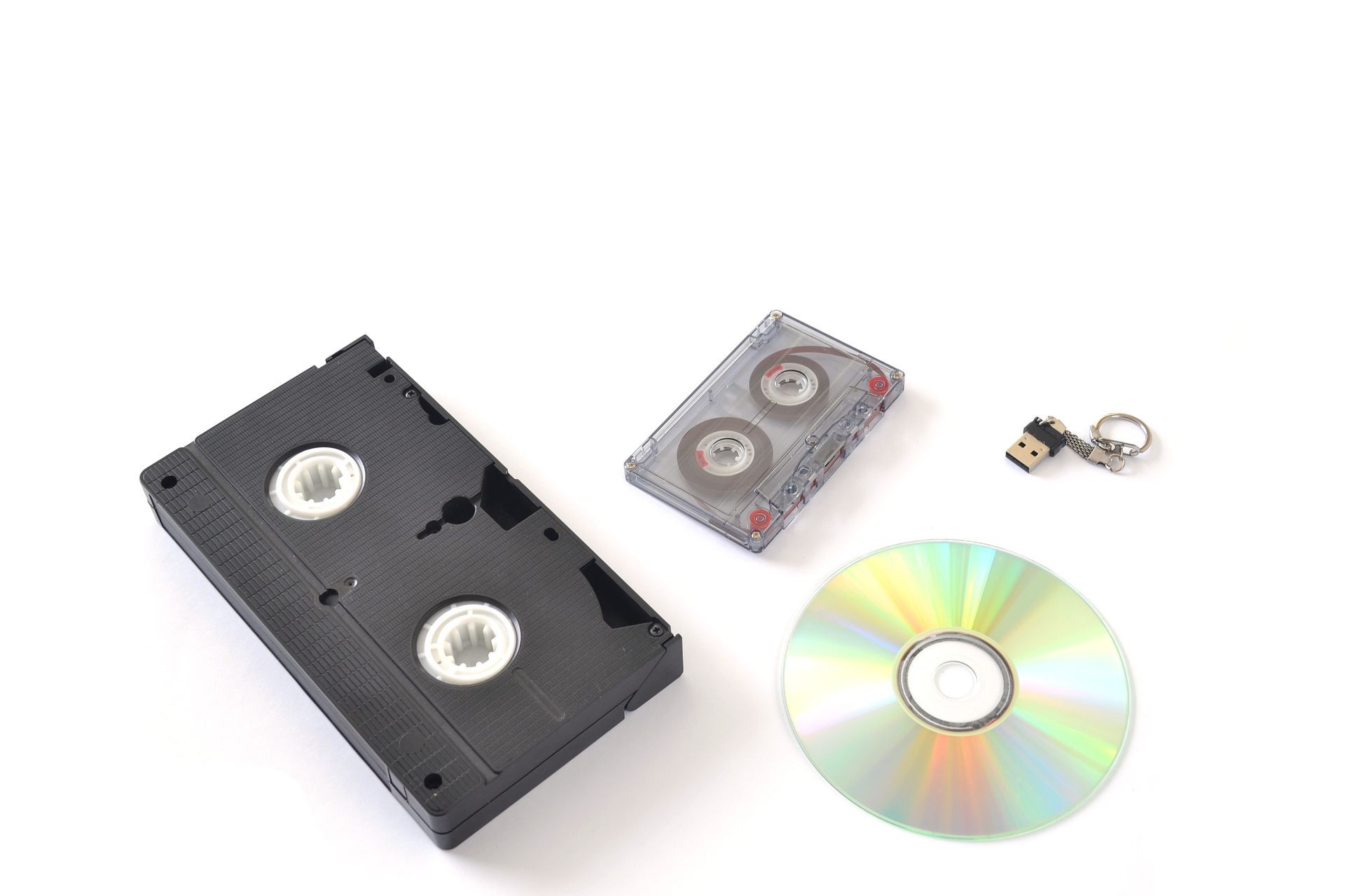 Audio cassette, video cassette, CD and flash memory on a white background.